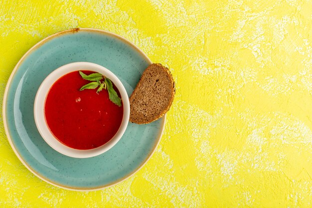 Vista superior deliciosa sopa de tomate com pão preto na mesa amarela, jantar de refeição de comida de sopa