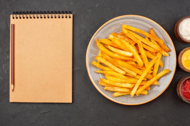 Vista superior deliciosas batatas fritas com temperos em hambúrguer de batata com piso escuro, prato fast-food