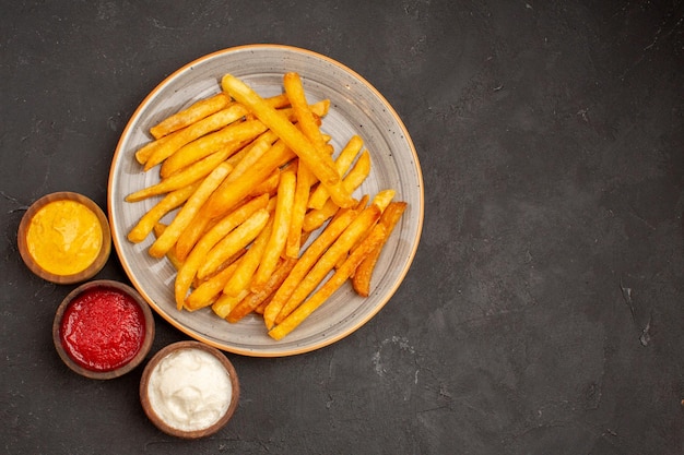 Foto grátis vista superior deliciosas batatas fritas com temperos em hambúrguer fast-food de batata prato escuro de mesa