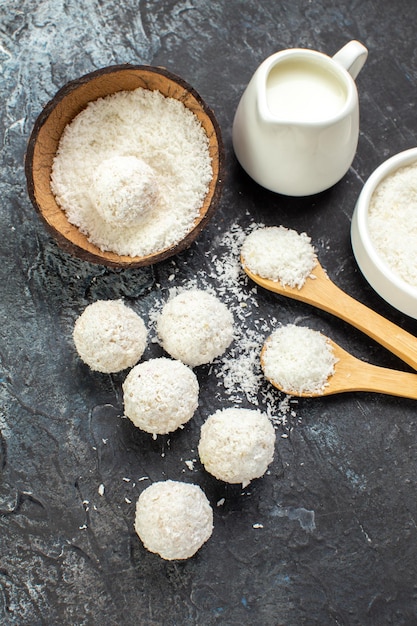 Vista superior deliciosas bolas de coco doces gostosos com leite em fundo escuro biscoito doce biscoito guloseima cor doce