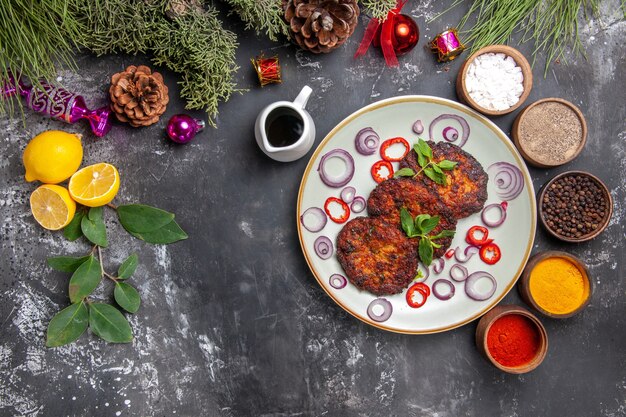 Vista superior deliciosas costeletas com anéis de cebola na foto de prato de carne com fundo cinza