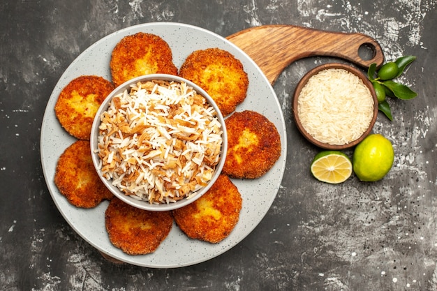 Vista superior deliciosas costeletas fritas com arroz cozido em um prato de carne rissole de superfície escura