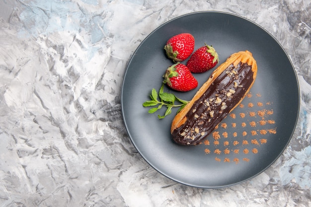 Vista superior deliciosas eclairs de chocolate com morangos em bolos de frutas leves