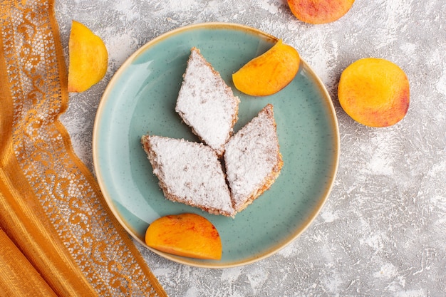 Vista superior deliciosas fatias de bolo com açúcar em pó e pêssegos fatiados dentro do prato sobre a mesa, bolo biscoito açúcar pastelaria doce assar