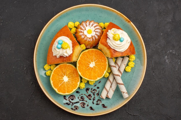 Vista superior deliciosas fatias de bolo com biscoitos e tangerinas fatiadas em um fundo escuro torta de frutas cítricas bolo biscoito chá doce