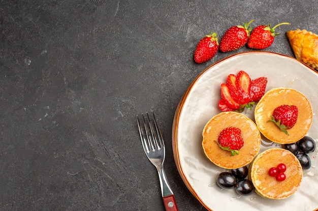 Vista superior deliciosas panquecas com frutas em piso escuro torta bolo de frutas doce