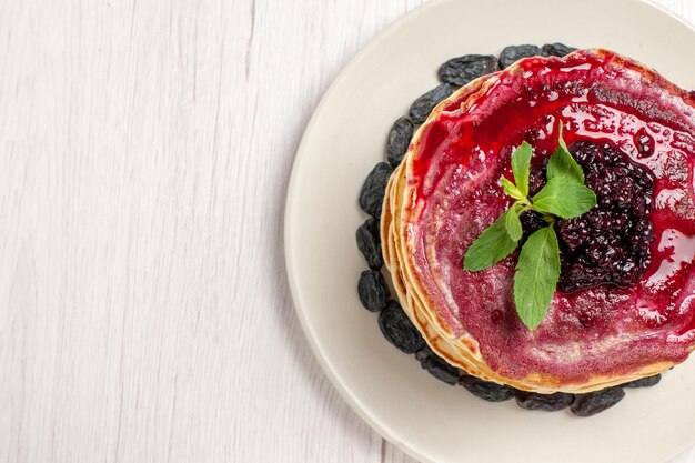 Vista superior deliciosas panquecas de geleia com passas e geleia de frutas na mesa branca bolo biscoito sobremesa geleia doce