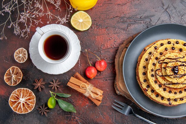 Vista superior deliciosas panquecas doces com chá na superfície escura