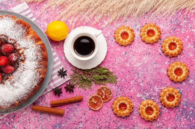 Vista superior delicioso bolo de morango com açúcar em pó com biscoitos e chá no fundo rosa claro bolo doce biscoito chá