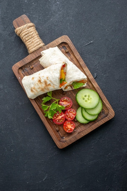 Vista superior delicioso sanduíche pita fatiado shaurma na tábua de corte superfície escura comida hambúrguer pão grelha lanche torrada refeição batatas fritas