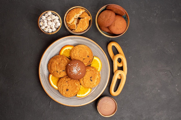 Vista superior deliciosos biscoitos de açúcar com laranjas frescas cortadas no fundo escuro biscoitos biscoito bolo de açúcar sobremesa doce