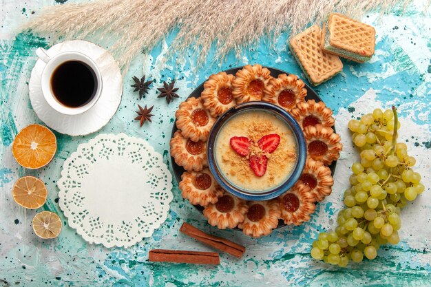 Vista superior deliciosos biscoitos de açúcar com waffles, xícara de café e sobremesa de morango na mesa azul
