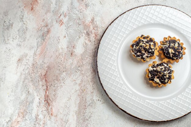 Vista superior deliciosos bolinhos com gotas de chocolate dentro do prato no fundo branco bolo de chá biscoito doce creme sobremesa