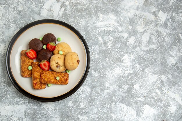 Vista superior deliciosos bolos com biscoitos e morangos no fundo branco biscoito bolo de açúcar torta doce chá