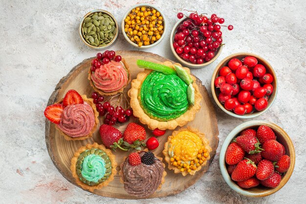 Vista superior deliciosos bolos cremosos com frutas frescas em uma torta de mesa branca sobremesa doce