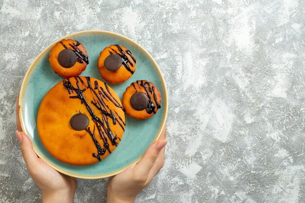 Vista superior deliciosos bolos de cacau com cobertura de chocolate dentro do prato na superfície branca bolo biscoito sobremesa torta de biscoitos doces