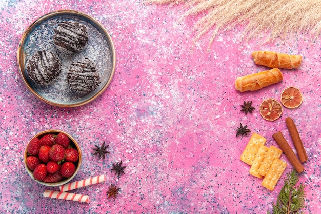 Foto grátis vista superior deliciosos bolos de chocolate com rosquinhas em rosa