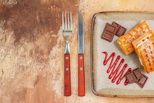 Vista superior deliciosos bolos de waffle com barras de chocolate no fundo marrom