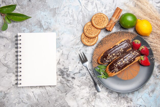 Vista superior deliciosos choco eclairs com biscoitos no bolo de mesa branco biscoito de sobremesa