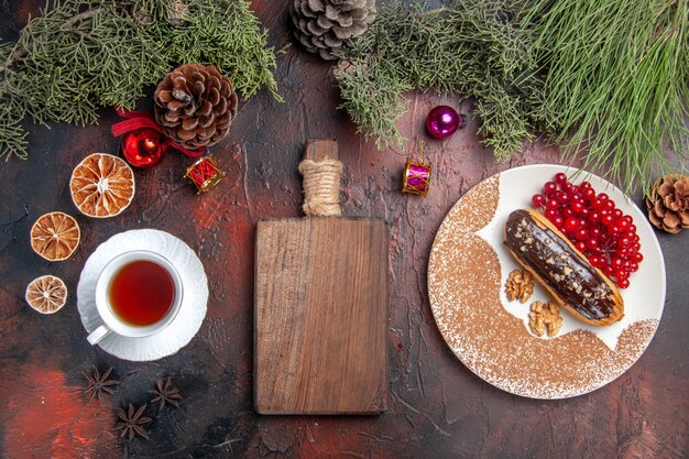 Vista superior deliciosos choco eclairs com chá e frutas vermelhas na mesa escura torta doce sobremesa bolo