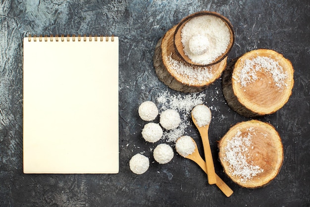 Vista superior deliciosos doces de coco com pedaços de madeira em fundo escuro chá frutas coloridas guloseimas doces