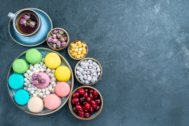 Vista superior deliciosos macarons franceses com uma xícara de chá no escuro