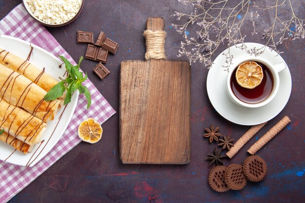 Vista superior deliciosos pastéis doces com xícara de chá e biscoitos no espaço escuro