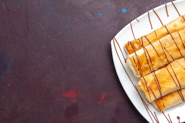 Vista superior deliciosos pastéis doces dentro do prato no espaço escuro