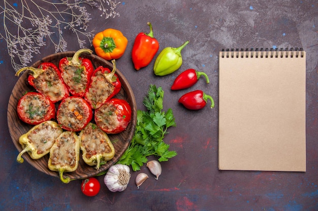 Vista superior deliciosos pimentões assados no prato com recheio de carne e vegetais no fundo escuro.