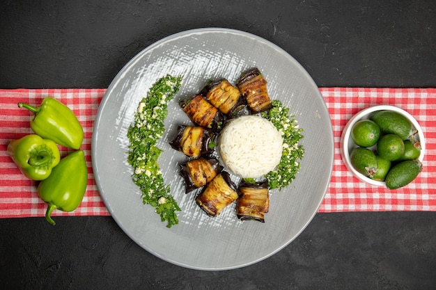 Vista superior deliciosos rolos de berinjela prato cozido com arroz na superfície escura cozinhando arroz óleo vegetal comida