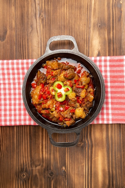 Vista superior distante refeição de vegetais cozidos, incluindo vegetais e carne dentro de uma mesa de madeira marrom