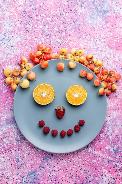 Foto grátis vista superior distante sorriso de frutas dentro do prato em rosa brilhante mesa fruta fresca madura cor suave