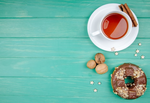 Vista superior do biscoito de chocolate e xícara de chá com canela no saquinho de chá com nozes no verde com espaço de cópia