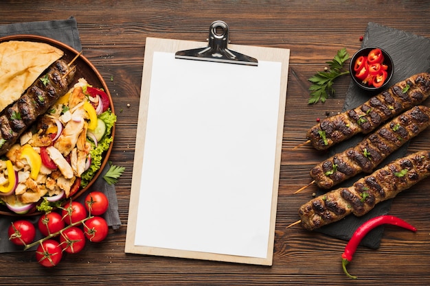 Vista superior do bloco de notas com deliciosos kebabs e tomates
