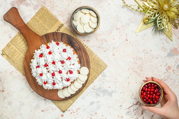 Vista superior do bolo com creme de confeiteiro branco na placa de madeira no jornal e enfeite de natal