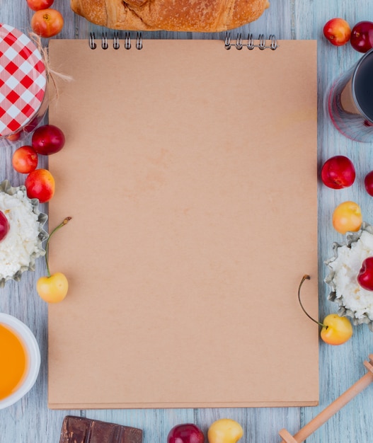 Vista superior do caderno e queijo cottage com cerejas frescas de amarelas e vermelhas maduras, dispostas em cinza