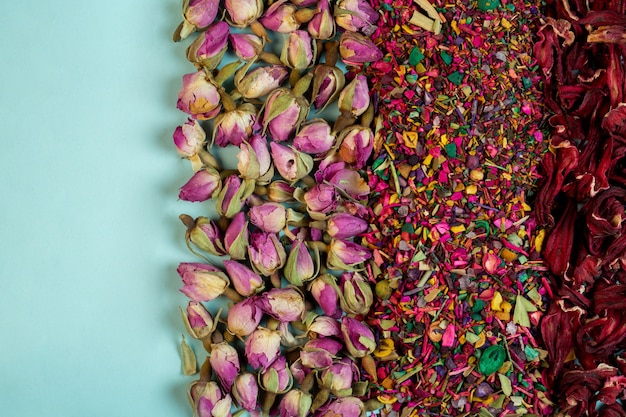 Vista superior do chá de ervas misto floresce pétalas de rosa secas botões de rosa e ervas em azul