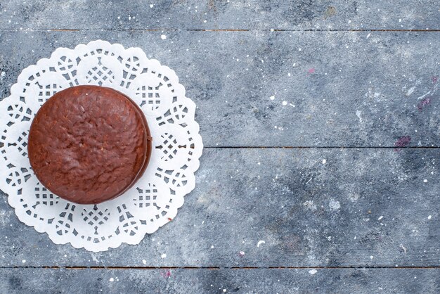 Vista superior do delicioso bolo de chocolate redondo formado isolado em uma mesa cinza, asse bolo de chocolate biscoito doce de cacau