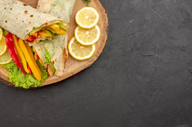 Vista superior do delicioso sanduíche de carne shaurma fatiado com rodelas de limão na mesa preta