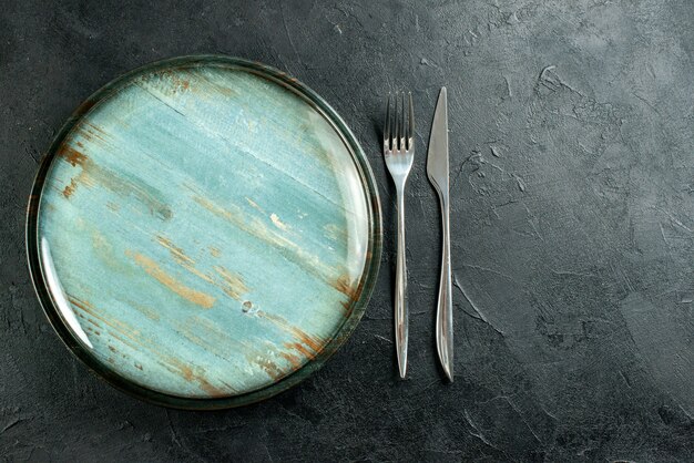 Vista superior do garfo de prato redondo de aço e faca de jantar em mesa preta grátis