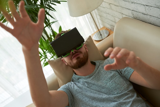 Vista superior do homem testando o aplicativo vr em seu sofá em casa