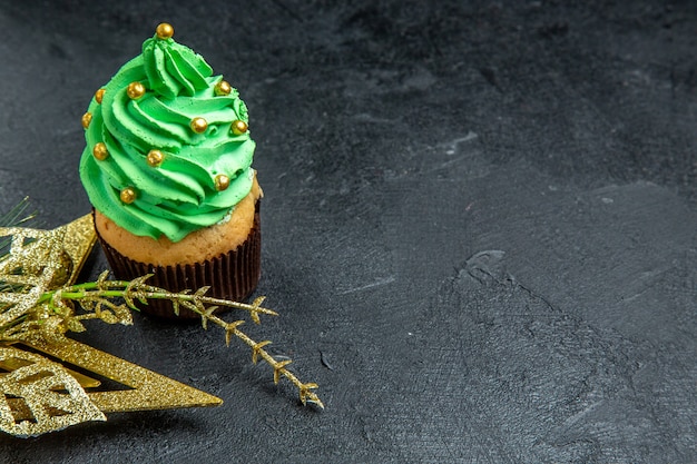 Vista superior do mini cupcake da árvore de natal e enfeite dourado pendurado na superfície escura