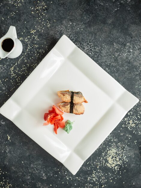 vista superior do nigiri de peixe frito servido com gengibre e wasabi