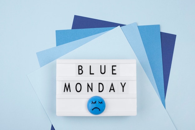 Vista superior do papel com rosto triste e caixa de luz para segunda-feira azul