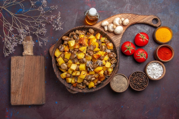 Vista superior do prato com comida com cogumelos e óleo de batata em garrafa tomate cogumelos especiarias coloridas e tábua de cortar