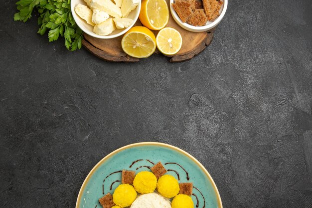 Vista superior do queijo branco com balas de bolo e rodelas de limão em comida de leite de fruta de superfície escura