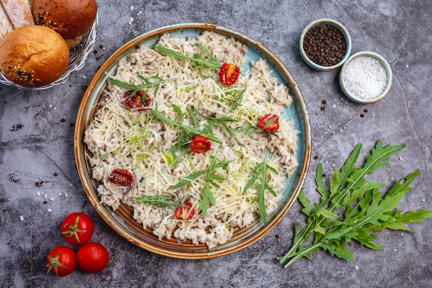 Foto grátis vista superior do risoto de cogumelos, guarnecido com queijo ralado, tomate seco e folhas