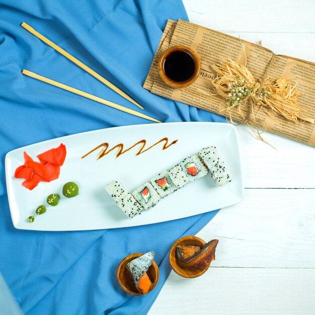 Vista superior do rolo de sushi de cozinha tradicional japonesa com salmão abacate e creme de queijo em azul e branco