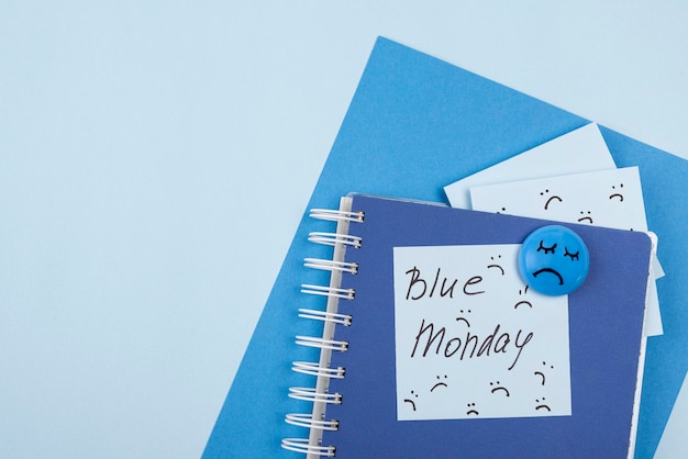 Vista superior do rosto triste com caderno e notas adesivas para segunda-feira azul