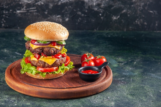 Vista superior do saboroso sanduíche de ketchup de tomate em uma tábua de madeira no lado direito em uma superfície de cor escura